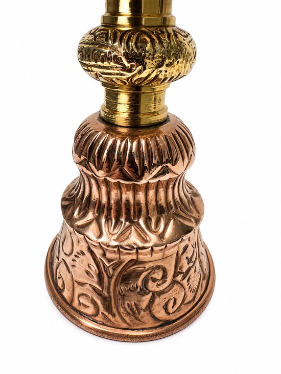 De onderkant van een Tibetaanse boterlamp, van koper met ingewikkeld reliëf.