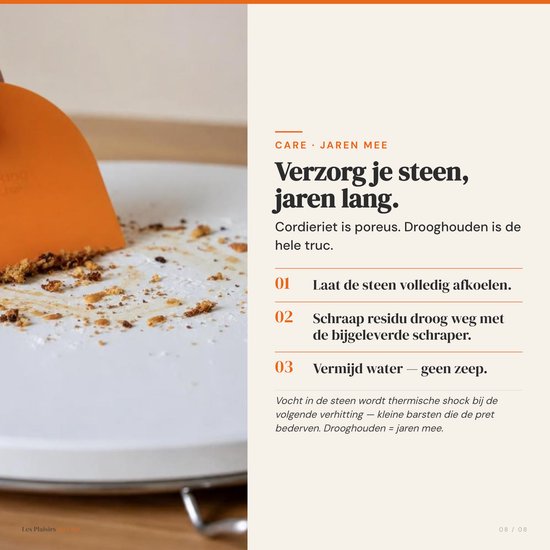 Oranje deegschraper die kruimels van een witte steen schraapt.