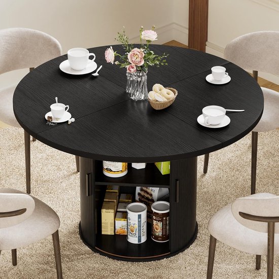 Zwarte ronde eettafel voor 4 personen, met vaas bloemen, kopjes en schotels. Met opbergruimte in de voet.