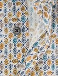 Detail van een overhemd met een print van bladeren, met een knoop en openvallende stof.