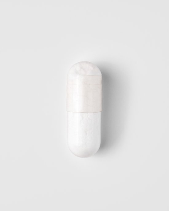 Een witte capsule, gesplitst in twee gelijke delen met een licht crèmekleurige bovenkant.