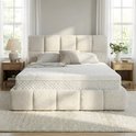 Een opgemaakt bed met een wit matras en een opvallend gestructureerd, crème-kleurig bedframe en hoofdbord, in een slaapkamer.
