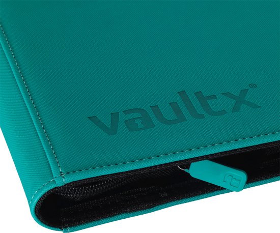 Close-up van een blauwgroene Vault X binder, met reliëflogo en turquoise ritslip.