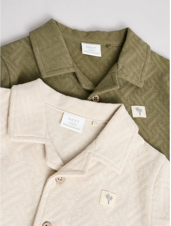 Close-up van de kragen van beige en groene babyrompertjes met visgraatpatroon.