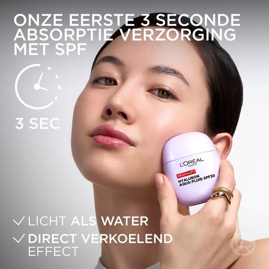Een vrouw houdt een paars L'Oréal Revitalift Hyaluron Aqua-Fluid SPF30 flesje vast.