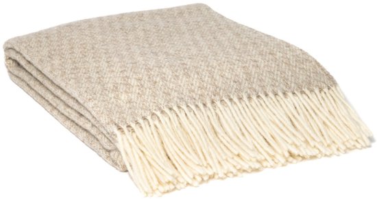 Opgevouwen beige plaid met visgraatmotief en crèmefranjes.