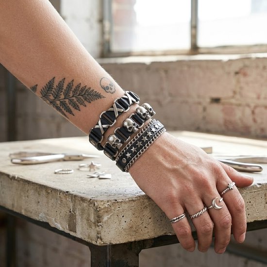 Zwarte PU leren armbanden met zilverkleurige details zoals schedels en sterren, gedragen door een man met tatoeages op zijn arm.