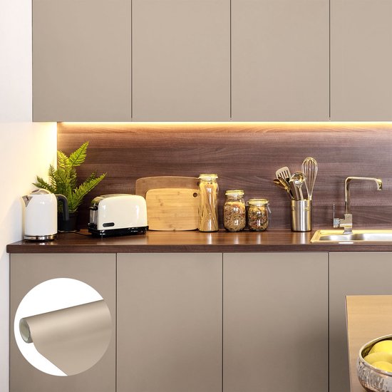 Taupe keukenkastjes met houten accenten, onderbouwverlichting, witte waterkoker, broodrooster en keukenbenodigdheden.