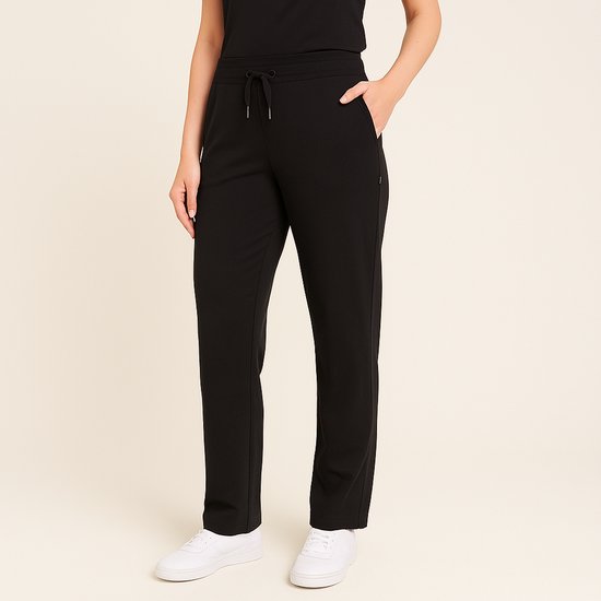 Zwarte joggingbroek met trekkoord, zakken en witte sneakers.