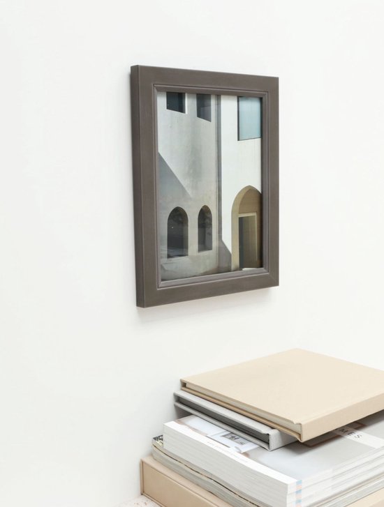 Grijze fotolijst met een foto van een gebouw, staand op een stapel boeken.