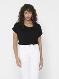 Model in zwart T-shirt met opgerolde mouwen en witte jeans.