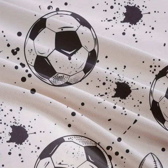 Gedetailleerde close-up van een zwart-wit voetbalprint op een crèmekleurige stof met spatten.