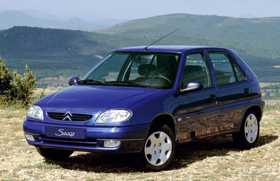 Citroën Saxo bleue à hayon garée sur un terrain caillouteux.