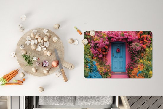 Set de table imprimé d'une maison rose, d'une porte bleue et de fleurs, à côté d'une planche à découper avec des légumes.