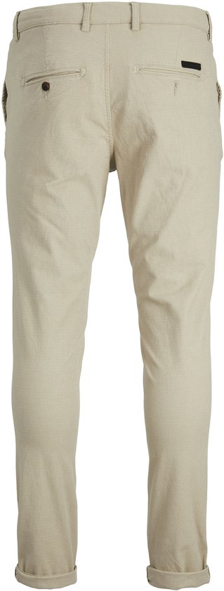 Achterkant van een lichtbeige chino met een subtiel ruitpatroon, twee paspelzakken en een label.