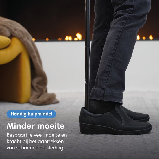 Dichtbij van voeten van een persoon die een schoen aantrekt met een lange zwarte schoenlepel.