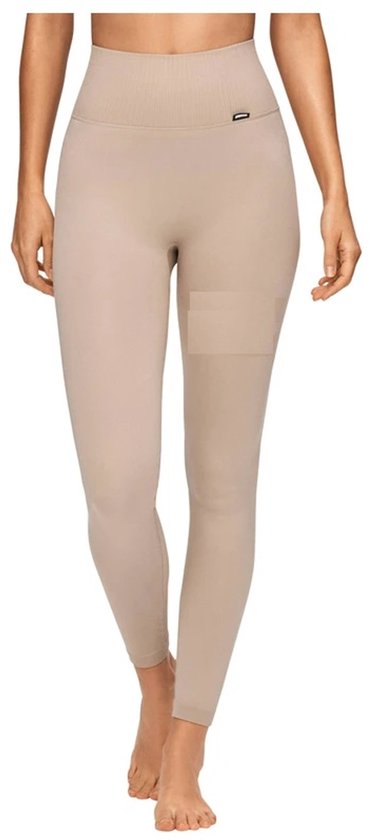 Een vrouw draagt een naadloze, hoog getailleerde sportlegging in de kleur Simply Taupe. De legging is tot op de enkels en heeft een ribgebreide tailleband.