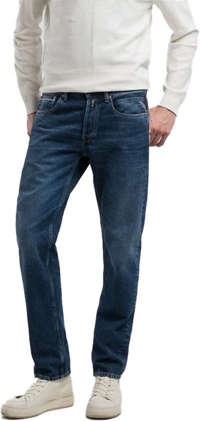 Mannequin portant un jean Replay bleu foncé et un pull blanc tricoté, main dans la poche.