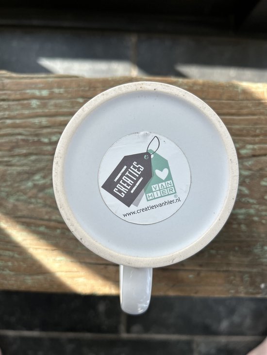 Onderkant witte mok met label 'Creaties van Hier' en website www.creatiesvanhier.nl