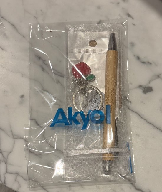 Een houten pen met een rode appel sleutelhanger, verpakt in plastic met het Akyol logo.