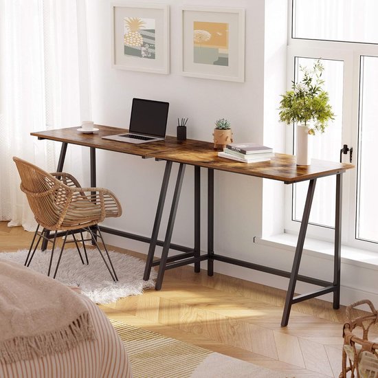 Lichtbruin houten bureau met zwart frame, in een woonkamer met rotan stoel.