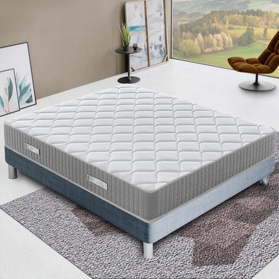 Matelas blanc avec côtés gris, posé sur un sommier bleu-gris à pieds métalliques.