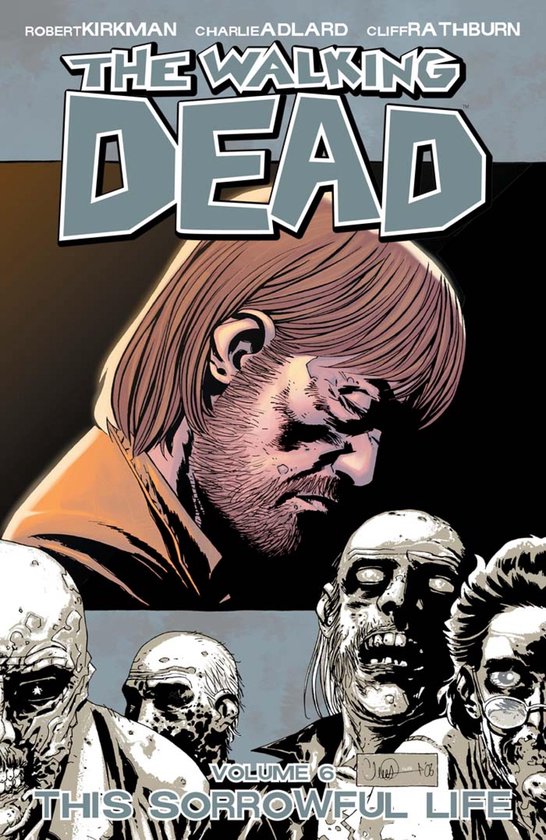 Cover van The Walking Dead Vol. 6: This Sorrowful Life, met een getekende man met bruin haar, een baard en gesloten ogen, omringd door zombies.