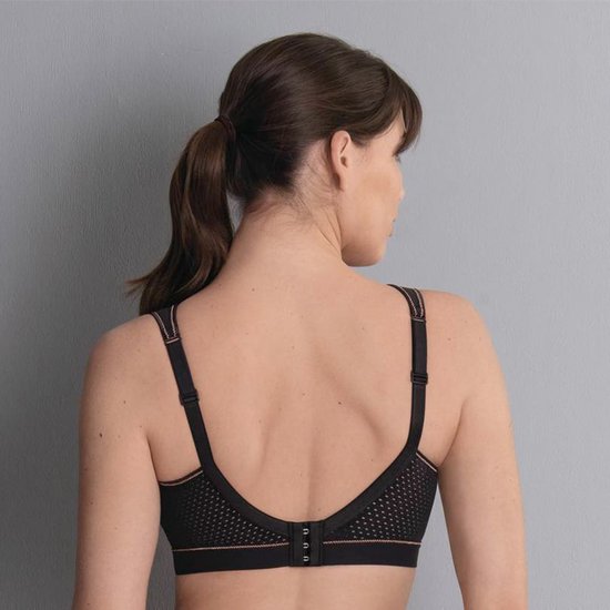 Model van achteren gezien in zwarte sportbeha met koperkleurige biezen en mesh.