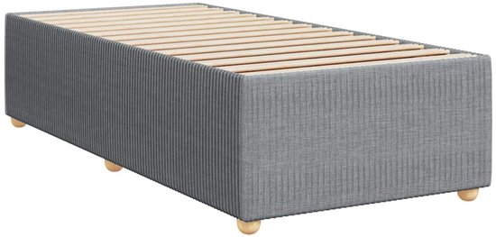 Sommier gris clair en tissu côtelé, avec des lattes en bois et des pieds ronds.