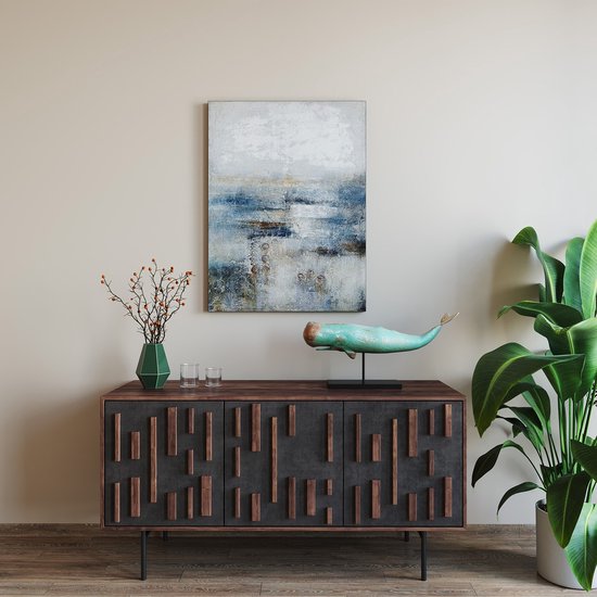 Decoratief beeld van een verweerde turquoise en bruine walvis op een zwarte standaard, geplaatst op een dressoir.