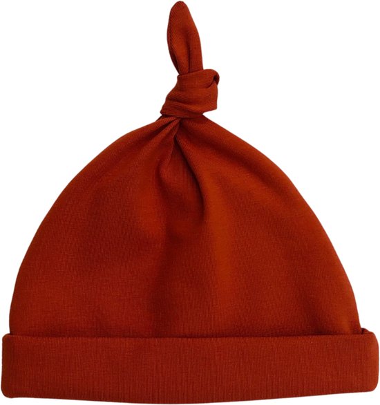Baby muts in terra-kleur met een knoop bovenop.