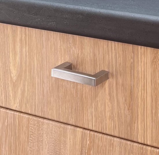 Zilverkleurige, rechthoekige handgreep op een houten kastdeur.