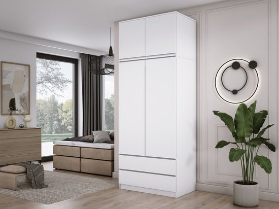 Witte kledingkast met opzetkast en twee lades in een slaapkamer.
