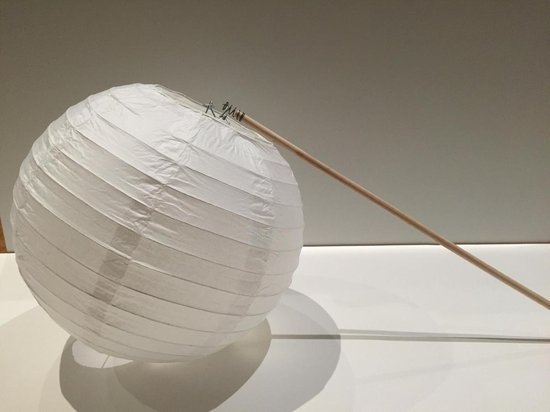 Witte ronde papieren lampion bevestigd aan een houten lampionstokje.