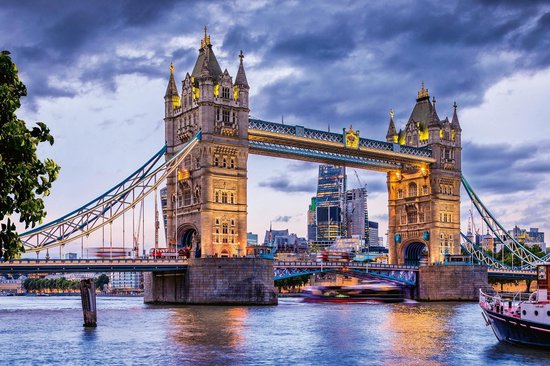 Le Tower Bridge au crépuscule avec des bateaux sur la Tamise et des bus à impériale rouges.