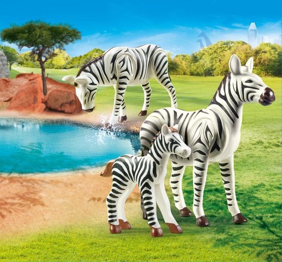 Drie Playmobil speelgoed zebra's met zwart-witte strepen bij een waterplas in een dierentuin decor.