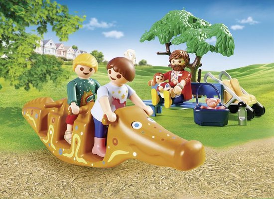 Playmobil figuren spelen op een oranje krokodil schommel dier in een buitenomgeving.
