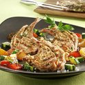 Gegrilde lamskoteletten met gegrilde courgette, aardappelen en paprika, gegarneerd met peterselie.