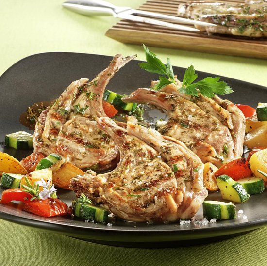 Gegrilde lamskoteletten met gegrilde courgette, aardappelen en paprika, gegarneerd met peterselie.