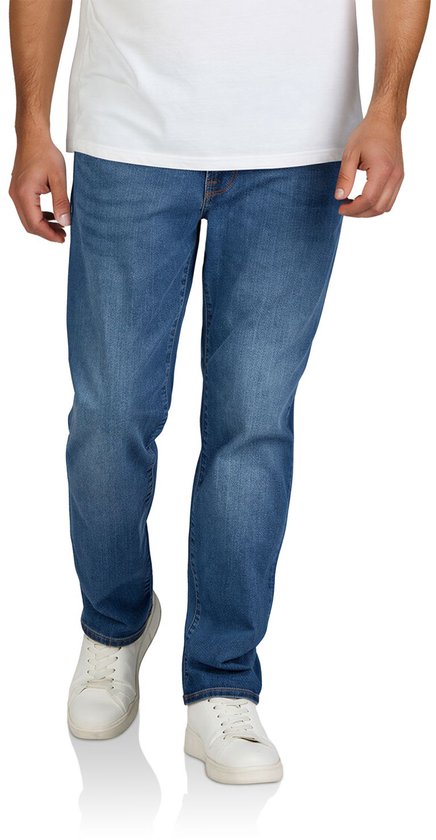 Man in een blauwe spijkerbroek, wit T-shirt en witte sneakers, staand vooraanzicht.