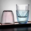 Un verre rose à l'envers à côté de deux verres bleus empilés remplis d'eau.