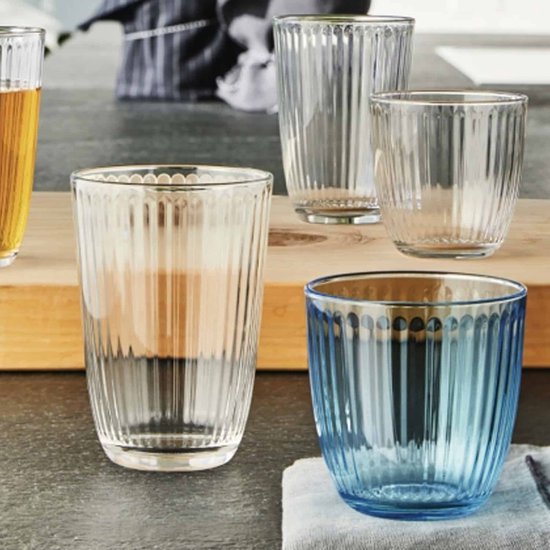 Ensemble de différents verres tumbler côtelés sur une planche en bois, en verre transparent et bleu.