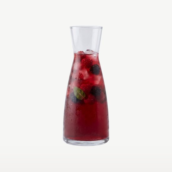 Glazen karaf gevuld met rood fruit, ijs en munt.
