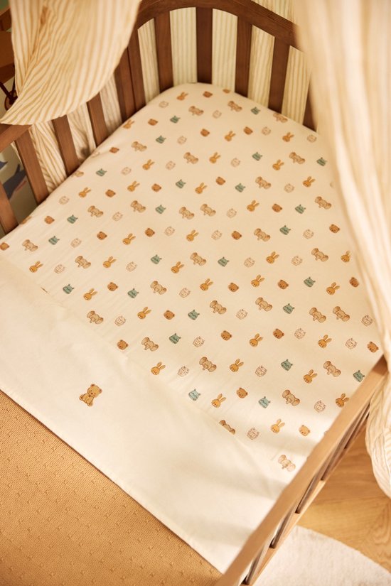 Ledikant met een hoeslaken met een dierenprint. Wit met kleine beige konijnen, blauwe nijlpaarden en bruine beren.