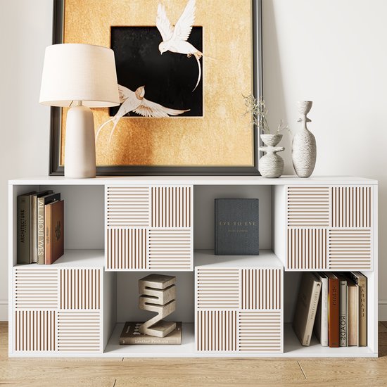 Witte kast met boeken en decoraties. Vier vakken hebben een patroon van verticale ribbels in vierkanten.