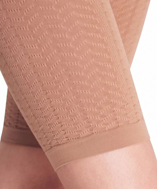 Detailopname van een huidkleurige, naadloze corrigerende legging met een fijn, geweven patroon.