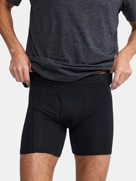 Zwarte sportboxershort met 6-inch pijpen en een elastische tailleband, gedragen door een man in een grijs T-shirt.
