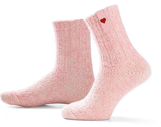 Paar roze gebreide sokken op kuithoogte, elk met een label met een rood hart.