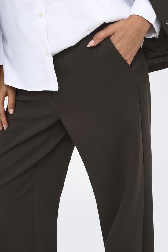 Close-up van de zak van de donkerbruine pantalon met een wit overhemd.