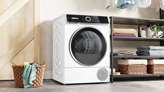 Bosch Serie 6 warmtepompdroger in een wasruimte met rekken vol handdoeken en een wasmand.